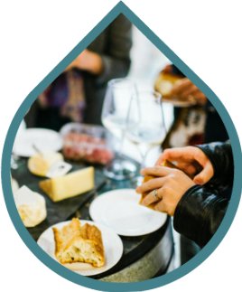 Close-up of people sharing bread and cheese at a table, with wine glasses and food visible. The image is shaped like a water droplet with a blue outline. Close-up of people sharing bread and cheese at a table, with wine glasses and food visible. The image is shaped like a water droplet with a blue outline.