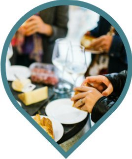 A close-up of people’s hands preparing food and holding plates at a gathering, with cheese, grapes, and wine glasses visible on the table. A close-up of people’s hands preparing food and holding plates at a gathering, with cheese, grapes, and wine glasses visible on the table.